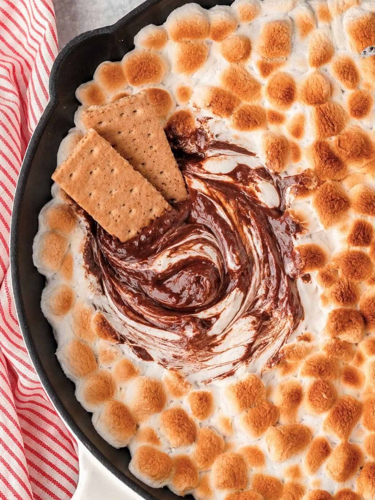 Graham crackers swirling chocolate in a cast iron skillet.