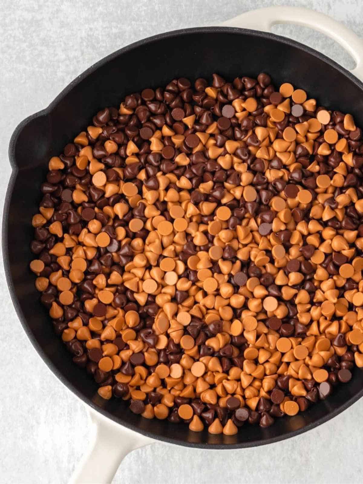 Chocolate chips and butterscotch morsels in a cast iron skillet.