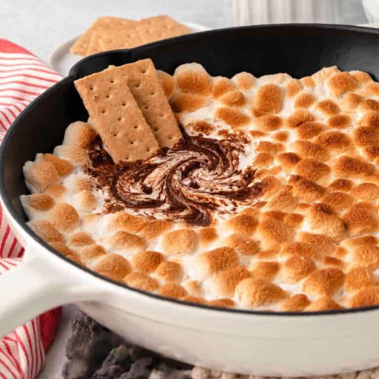 3-Ingredient S'mores Dip being swirled in a cast iron skillet with graham crackers.