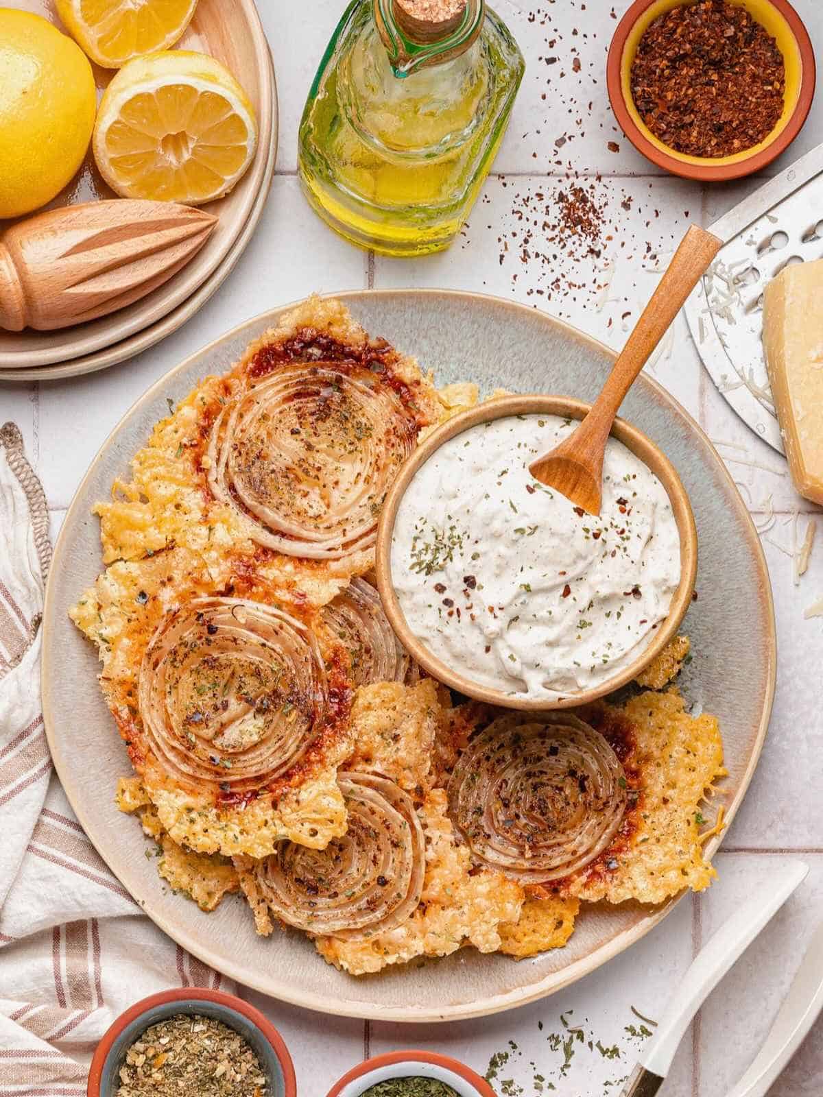 Onion ring chips being served on a plate with garlic herb dip.