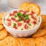 Hot Chipped Beef Dip in a white bowl surrounded by Ritz Crackers.