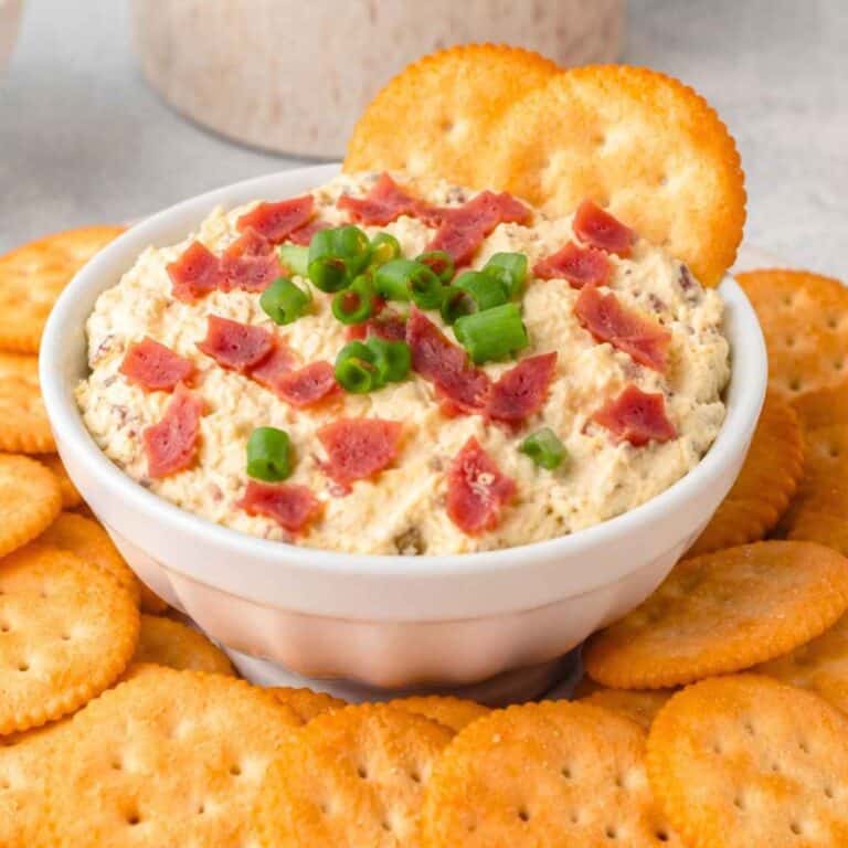 Hot Chipped Beef Dip in a white bowl surrounded by Ritz Crackers.