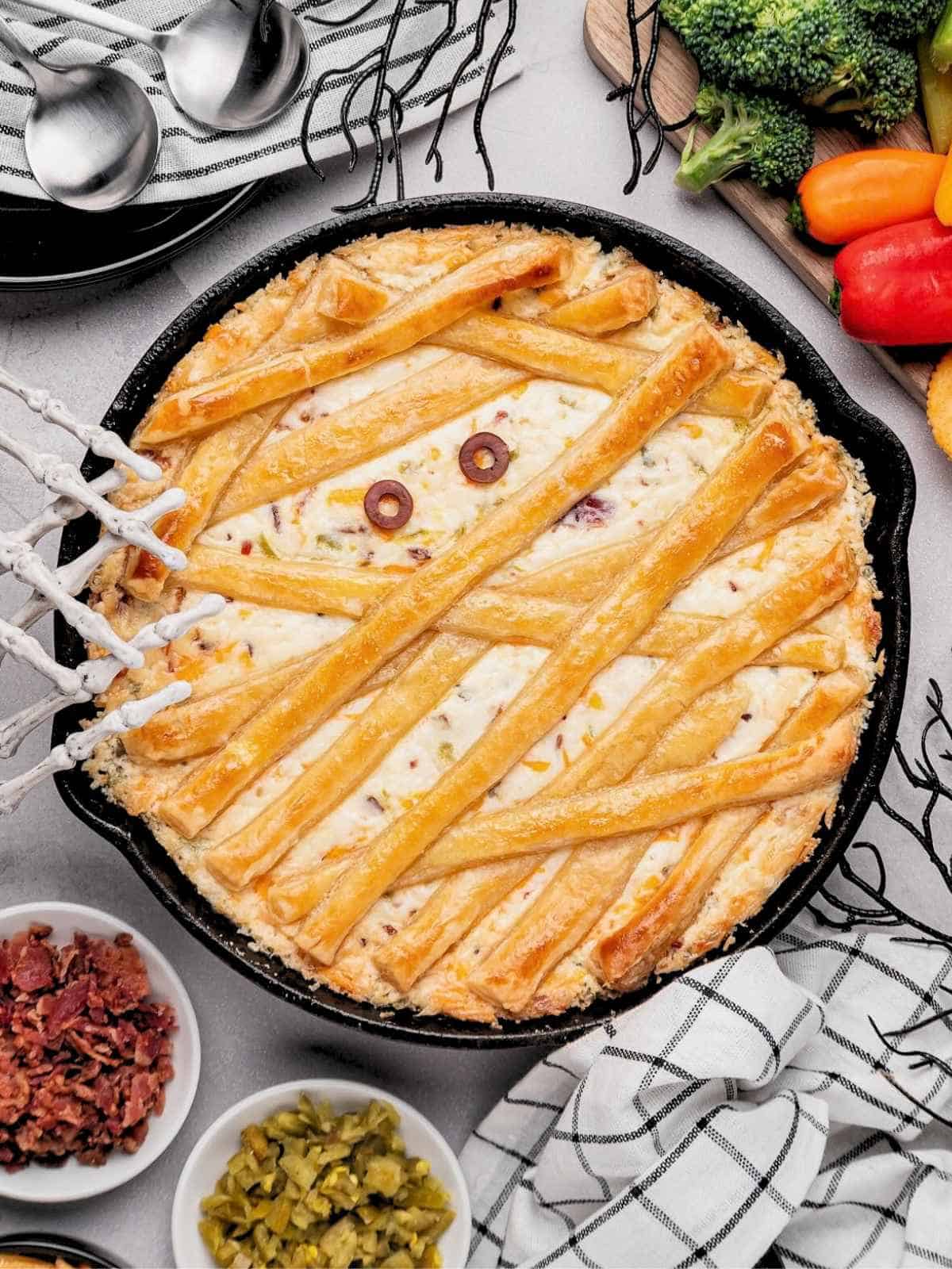 Mummy jalapeño popper dip surrounded by a scary tablescape.