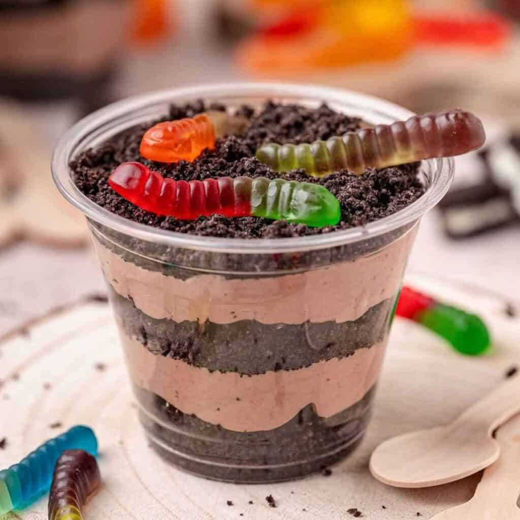 Gummy worms on top of Oreo Dirt Cake Cups that look like dirt.