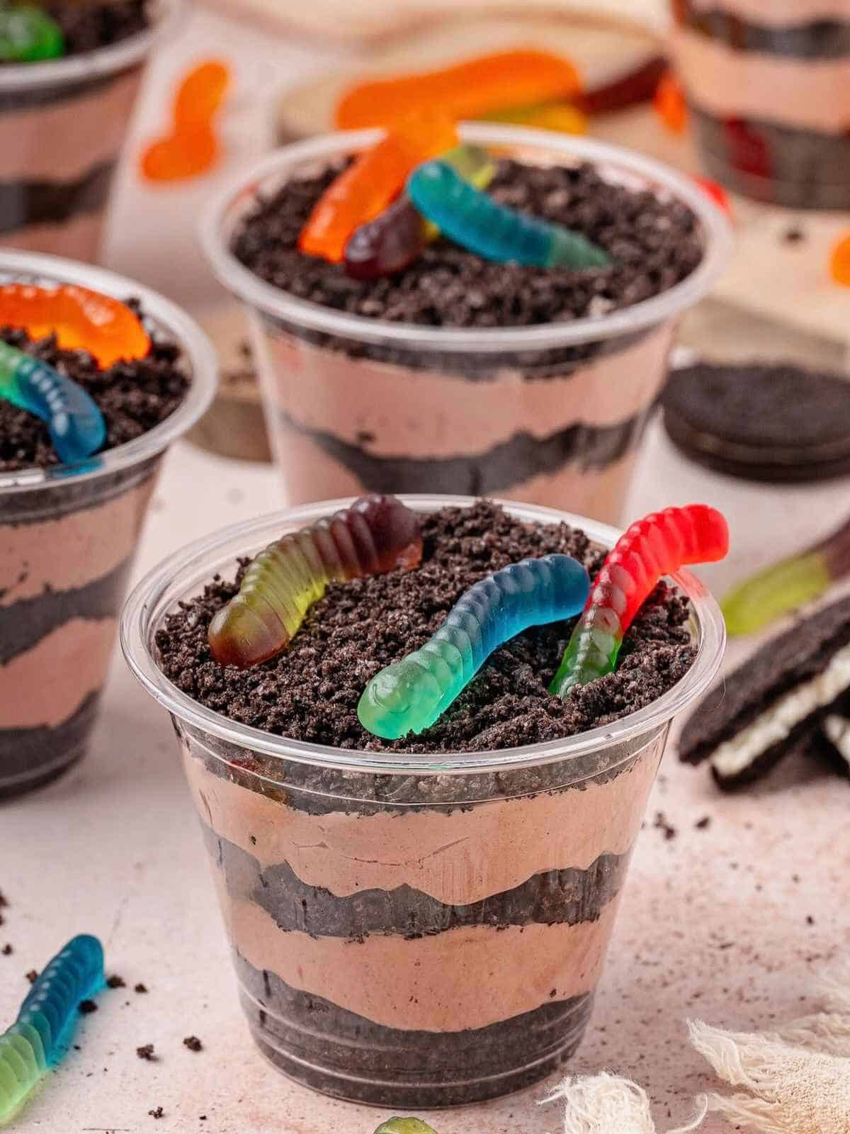 Individual cups filled with layered pudding, oreo cookie crumbs and topped with gummy worms.