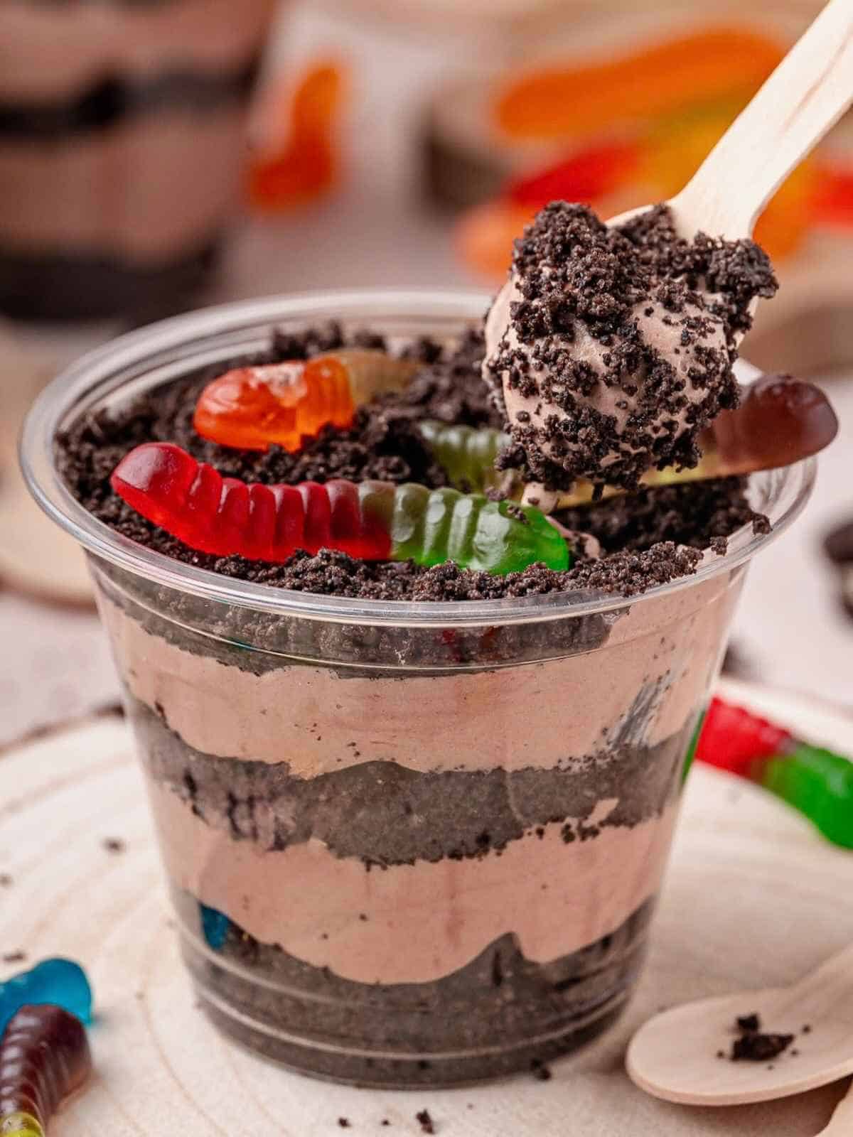 Spoon digging into dirt cake cups make with Oreo cookie crumbs.
